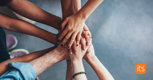 A group of people stacking hands on top of eachother to empower each other.