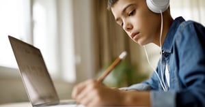 Young boy taking notes from his laptop