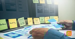 Henkilö kiinnittää seinälle post-it-laput, joihin on kirjoitettu käytettävyyttä ja saavutettavuutta koskevia termejä.