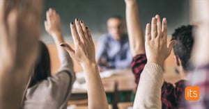 oppilaat, jotka nostavat kätensä ylös vastatakseen kysymykseen luokassa.