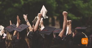 Graduate students celebrating and raising their hats in the air.