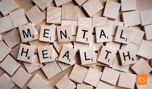 Scrabble chips made out of wood that spells out Mental Health.