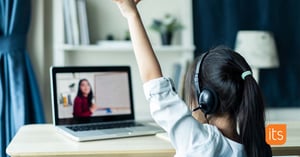 Student raising hand while attending class from home on a computer.