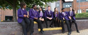 Students chatting while sat on a wall outside St Paul’s Catholic School